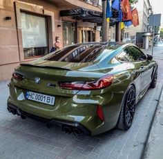 a green sports car parked on the side of the road in front of a building