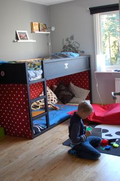 a young boy sitting on the floor in front of his bunk bed and playing with toys