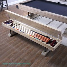 the pool table is made out of wood and has two cues, cues, and balls in it