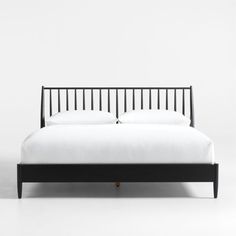 a bed with white sheets and black headboard on it's side, against a white wall