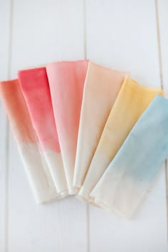 four different colored napkins on top of each other in front of a white background