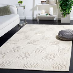 a living room area with a white rug and grey round pillow on the floor next to a couch