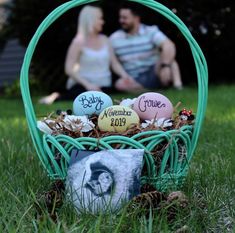 a basket filled with eggs sitting on top of a grass covered field next to a couple