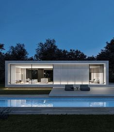 the house is lit up at night with its lights on and reflecting in the pool