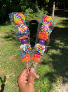 two candy lollipops in clear plastic containers with colorful candies and sprinkles on them