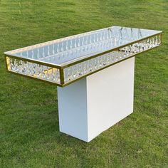 a white bench with gold trim on top in the grass