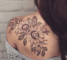 a woman with a sunflower tattoo on her upper back shoulder and arm, looking down at the ground