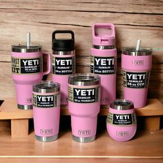 pink yeti tumblers sitting next to each other on a wooden shelf in front of a wood wall