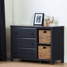 a black dresser with three baskets on top of it and a framed photo next to it