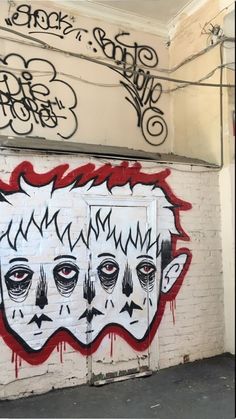 graffiti on the side of a white brick building with two faces painted in black and red