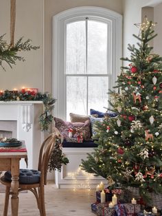 a decorated christmas tree sitting in front of a window next to a table and chair