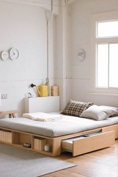 a bed with two drawers underneath it in a room next to a wall clock and window