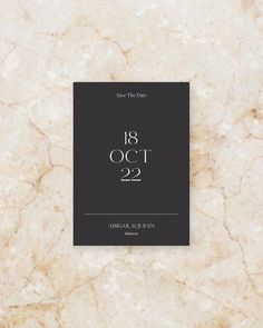 an elegant save the date card is displayed on a marble background with white and black lettering