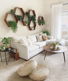 a living room filled with white furniture and lots of greenery on the wall above