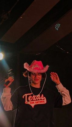 a woman wearing a pink cowboy hat on stage