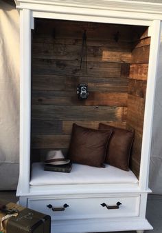 a white cabinet with two brown pillows and a hat on it's top shelf