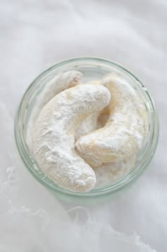 a bowl filled with powdered donuts sitting on top of a white table cloth