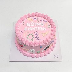 a pink birthday cake sitting on top of a white table next to a sign that says going eighteen