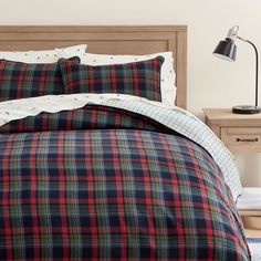 a bed with plaid comforter and pillows in a bedroom