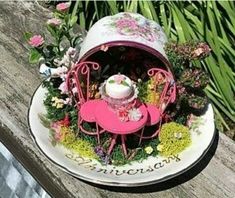 a small pink table and chair with flowers on the top is sitting on a wooden bench