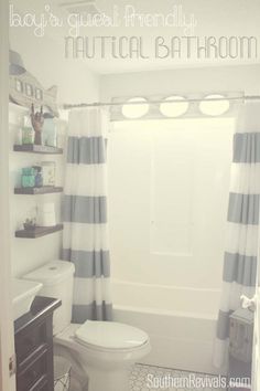 a white toilet sitting next to a bath tub under a bathroom window covered in blue and white striped curtains