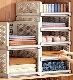 a person reaching for folded towels in a closet with shelving and shelves on the wall