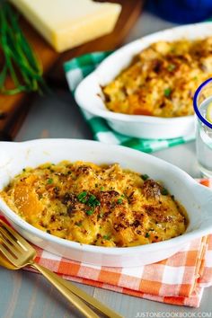 two white dishes filled with macaroni and cheese on top of a checkered table cloth