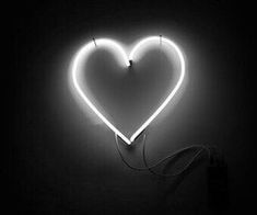 a heart - shaped neon sign is lit up in the dark with a cord attached to it