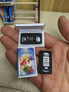 a hand holding an old nintendo game and a video game in it's packaging