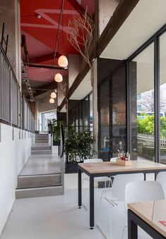 an empty restaurant with tables and chairs in front of large windows, stairs leading up to the second floor