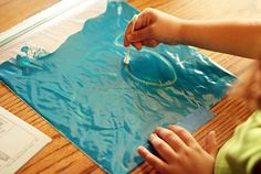 a child is painting on a piece of blue paper