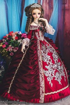 a doll dressed in a red and white dress with flowers on the floor next to it