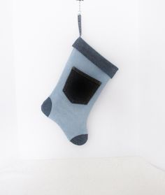 a blue sock hanging from a hook on a white wall with a black square in it