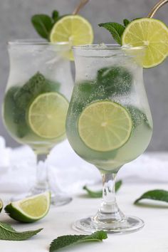 two glasses filled with lemonade and lime slices