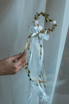 a person is holding a white ribbon with flowers on it and gold trim around the edge