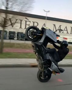 a man riding on the back of a motorcycle in front of a large store building