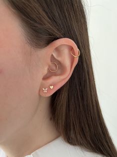 a close up of a person wearing an earring with two small hearts on it