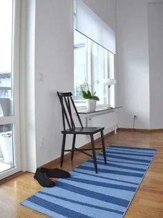 a room with a blue rug, chair and window in it's center area