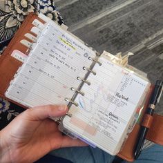 a person holding a planner and pen in their hand