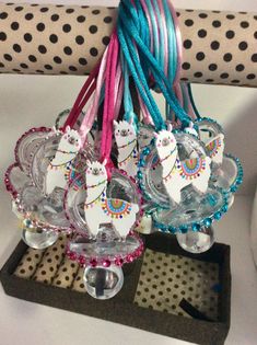 some llamas are sitting in glass bowls on a stand with beads and ribbons