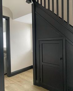 an open door leading to a bedroom with white walls and wood flooring on the bottom level