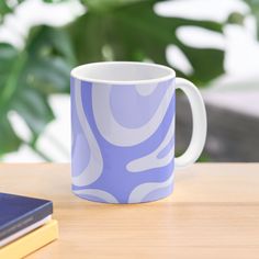 a blue and white coffee mug sitting on top of a wooden table next to a book