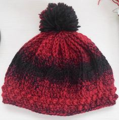 a red and black knitted hat sitting on top of a white table next to a clock