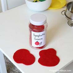 a jar of red liquid sitting on top of a table next to two heart shaped coasters