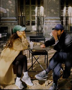 a man sitting next to a woman on top of a chair in front of a building