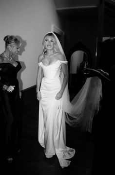 black and white photo of two women in wedding gowns, one wearing a veil