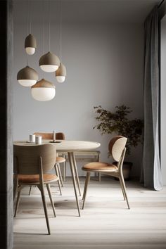 a dining room table and chairs with hanging lights above them in the corner of a room