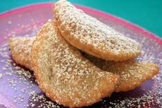 three powdered sugar cookies stacked on top of each other in front of a blue and pink plate