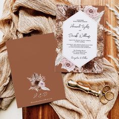 the wedding stationery is laid out on a wooden table with flowers and gold scissors