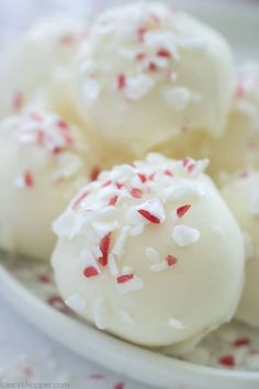 some white desserts with red and white sprinkles on them in a bowl